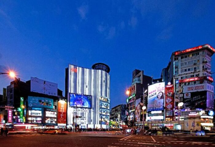 Night view of Tomorrow Hotel, a gay-friendly hotel. Bright lights illuminate city buildings. A vibrant scene for gay men's travel advice.