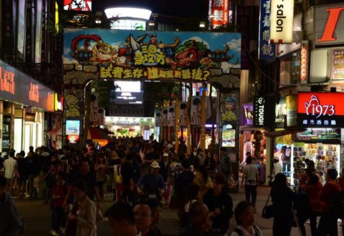 Night scene in Taipei, Taiwan. Crowded street with bright lights and signs. Gay-friendly Tomorrow Hotel nearby. Great gay travel destination.