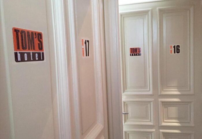 Tom's Hotel, a gay-friendly hotel. Room numbers 16 and 17 are visible on the doors. Tom's Hotel logo is on both doors.