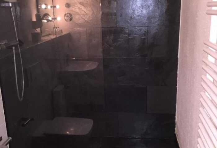 Tom's Hotel gay-friendly hotel bathroom. Black tile shower with glass door. Modern design at this gay hotel.