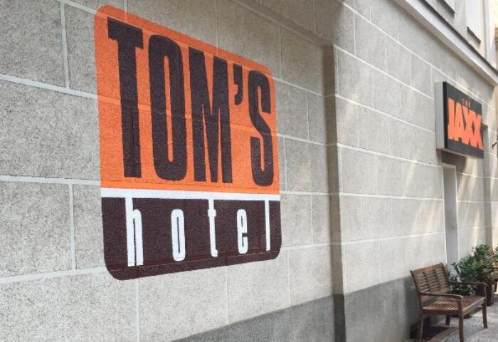 Tom's Hotel, a gay-friendly hotel. Exterior view showing the hotel's signage on the building's facade. Gay hotel for gay men travel.