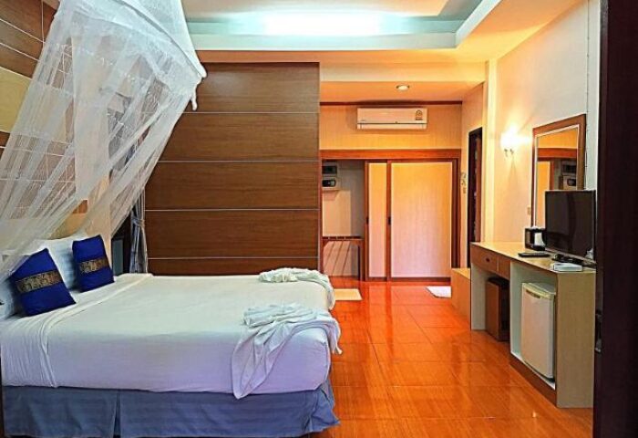 Tonsai Bay Resort gay-friendly hotel room. King bed with mosquito net, blue pillows, wooden floors, TV, and mini-fridge. Relaxing gay travel.