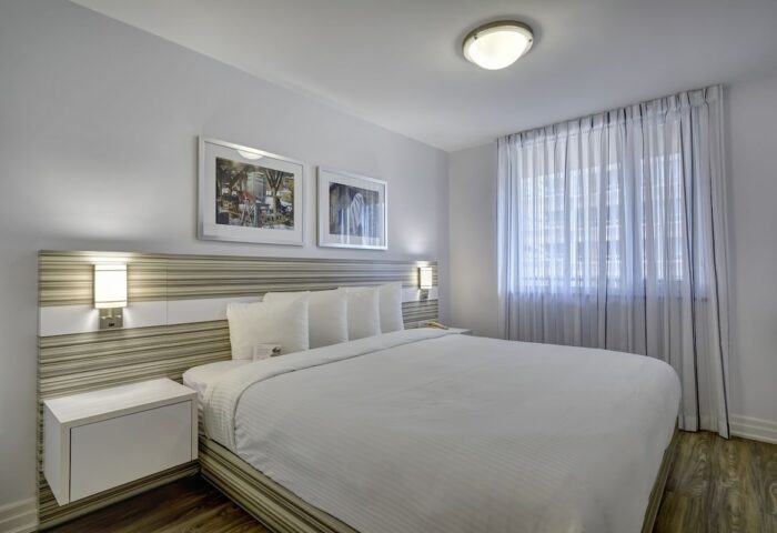 Town Inn Suites gay-friendly hotel room. Clean, modern design with white linens, striped headboard, and sheer curtains. Ideal for gay travel.
