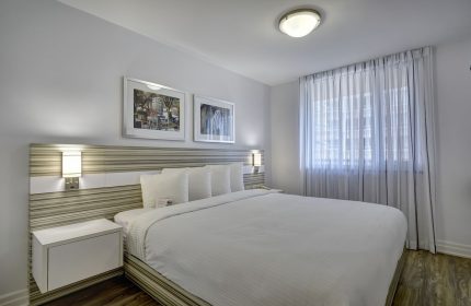 Town Inn Suites gay-friendly hotel room. Clean, modern design with white linens, striped headboard, and sheer curtains. Ideal for gay travel.