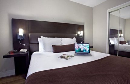 Town Inn Suites gay-friendly hotel room. Modern design with a laptop on the bed. Comfortable accommodations for gay travelers.