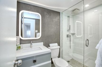 Town Inn Suites gay-friendly hotel bathroom. Modern design with illuminated mirror, glass shower, & sleek fixtures. Ideal for gay travel.