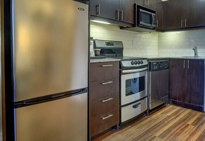 Town Inn Suites gay-friendly hotel kitchen. Stainless steel fridge, oven, microwave, and dishwasher. Dark wood cabinets and drawers.