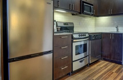 Town Inn Suites gay-friendly hotel kitchen. Stainless steel fridge, oven, microwave, and dishwasher. Dark wood cabinets and drawers.