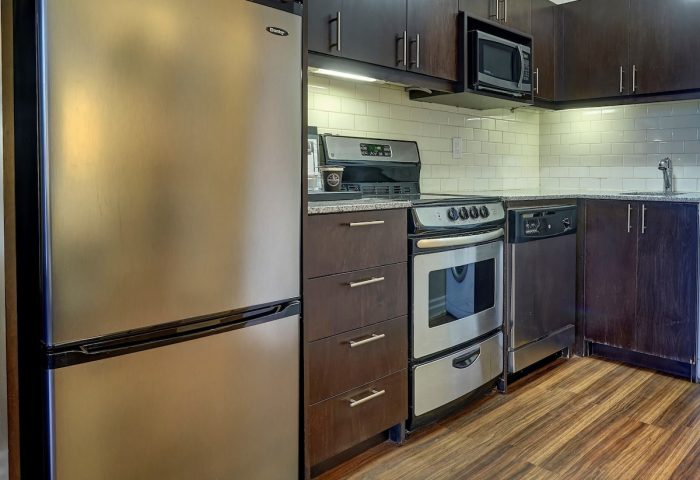 Town Inn Suites gay-friendly hotel kitchen. Stainless steel fridge, oven, microwave, and dishwasher. Dark wood cabinets and drawers.