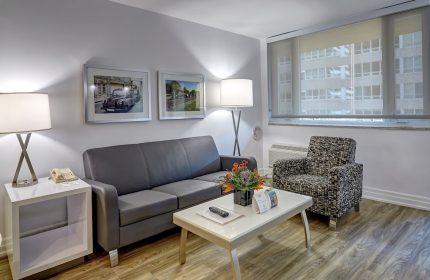 Town Inn Suites, a gay-friendly hotel: Suite living area with sofa, chair, table, and city view. Ideal for gay men's travel.