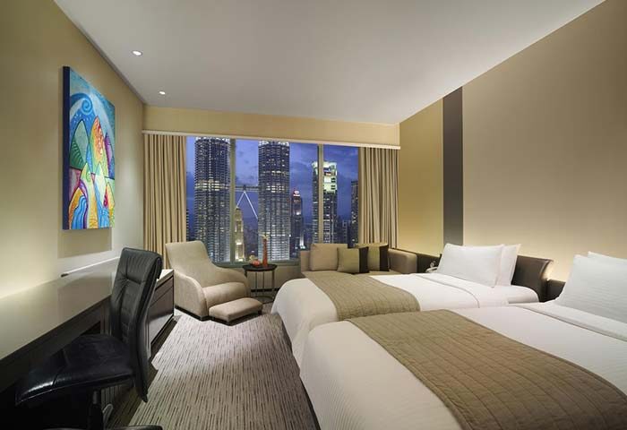 Traders Hotel Kuala Lumpur room. Twin beds, desk, chair, and city view. Gay-friendly hotel with modern decor, perfect for LGBTQ+ travelers.