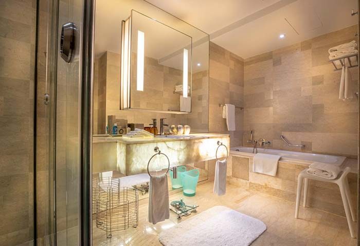 Traders Hotel Kuala Lumpur gay-friendly bathroom. Modern design with marble, bathtub, shower stall, and illuminated mirror. Upscale hotel.
