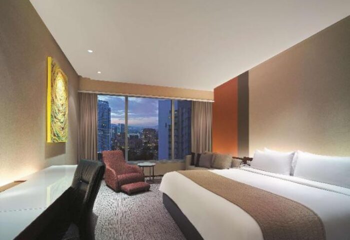 Traders Hotel Kuala Lumpur room. Gay-friendly hotel with a city view, desk, chair, and bed. Modern design for gay travelers.