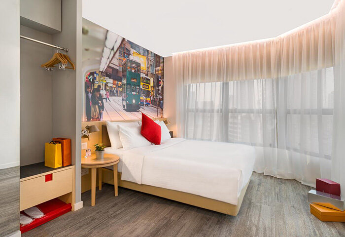 Travelodge Central Hollywood Road gay-friendly hotel room. Bed with Hong Kong street scene mural. Ideal for gay travel in Hong Kong.