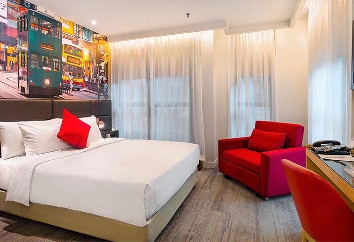Travelodge Central Hollywood Road gay-friendly hotel room. Features a double bed, Hong Kong tram mural, and red chair.