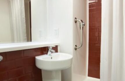 Bathroom interior at Travelodge London Vauxhall, a gay-friendly, pet-friendly hotel. Features a toilet, sink, and shower with curtain.