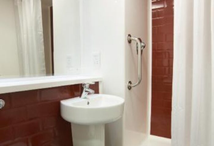 Bathroom interior at Travelodge London Vauxhall, a gay-friendly, pet-friendly hotel. Features a toilet, sink, and shower with curtain.