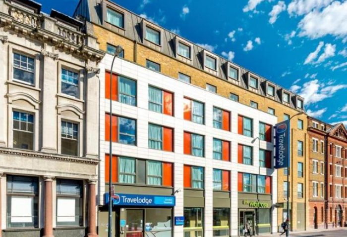 Travelodge London Vauxhall exterior. Gay-friendly, pet-friendly hotel. Modern facade with blue Travelodge sign, near Waitrose.
