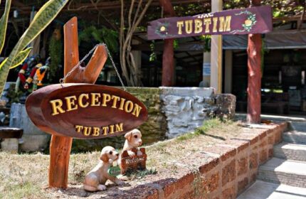 Reception sign at Gay-Friendly Hotel Tubtim Resort, a welcoming destination. Two puppy statues add charm to this tropical gay travel spot.