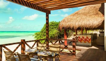 Turquoize at Hyatt Ziva Cancun adults-only all-inclusive gay-friendly hotel. Ocean view from a wooden deck with chairs and a thatched-roof bar.