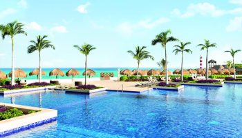 Turquoize at Hyatt Ziva Cancun adults-only all-inclusive resort pool. Gay-friendly hotel with beach, palm trees, and tiki umbrellas.