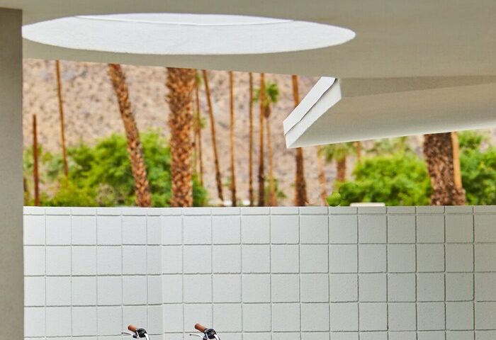 Twin Palms Resort, Palm Springs gay mens resort. Blue bikes against white tiled wall, palm trees. Gay-friendly hotel for men's travel.
