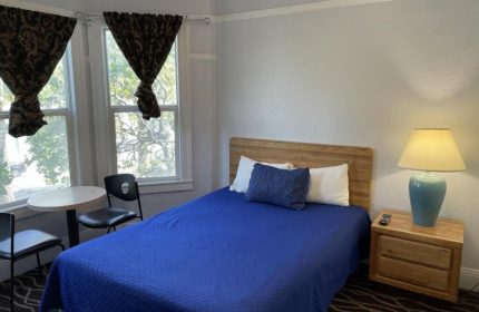 Twin Peaks Hotel room. Gay-friendly hotel with bed, nightstand, lamp, table, and chairs. Comfortable stay for gay travelers.
