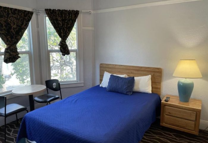 Twin Peaks Hotel room. Gay-friendly hotel with bed, nightstand, lamp, table, and chairs. Comfortable stay for gay travelers.