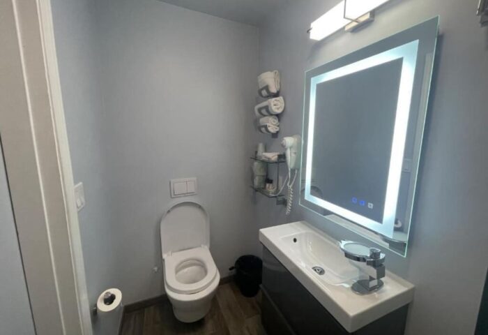 Bathroom at Gay-Friendly Twin Peaks Hotel. Modern design with toilet, sink, illuminated mirror, and gray walls. Gay travel accommodations.