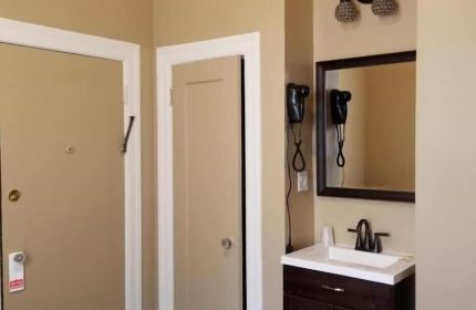 Twin Peaks Hotel room interior. Gay-friendly hotel with bathroom sink, mirror, hair dryer, and closet doors. Comfortable lodging.