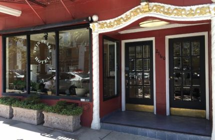 Twin Peaks Hotel entrance. Gay-friendly hotel with red facade, black doors, and gold trim. A welcoming choice for gay travelers.