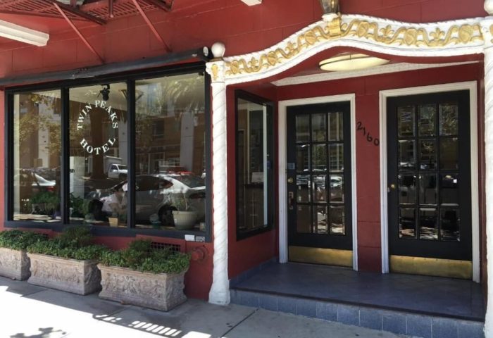 Twin Peaks Hotel entrance. Gay-friendly hotel with red facade, black doors, and gold trim. A welcoming choice for gay travelers.