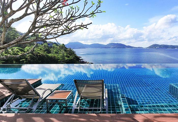 Infinity pool view at U Zenmaya Phuket Resort, a gay-friendly hotel. Ocean and mountain backdrop. Relaxing travel destination for gay men.