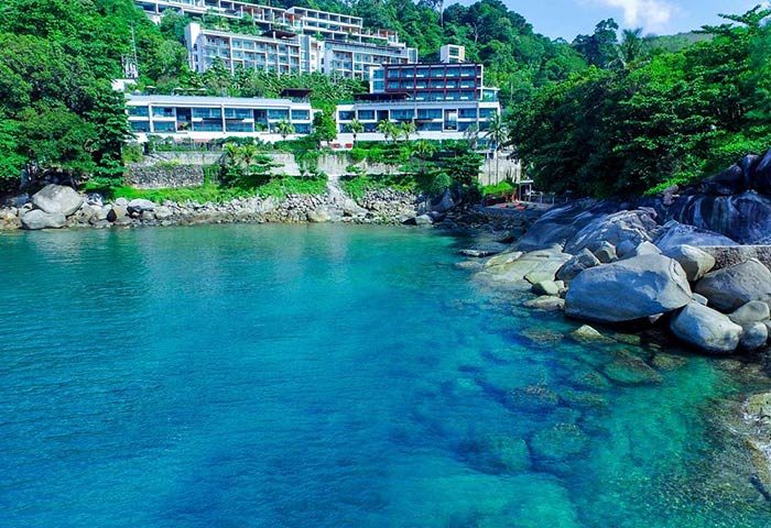 U Zenmaya Phuket Resort view. Gay-friendly hotel on a hillside overlooking turquoise water and rocks. A serene gay travel destination.