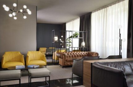 UNAHOTELS Century Milano gay-friendly hotel lobby. Stylish seating area with yellow armchairs and leather sofas, modern lighting.