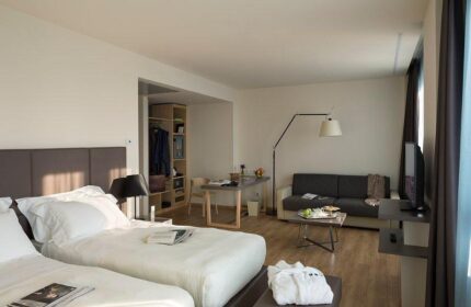 UNAHOTELS Century Milano gay-friendly hotel room. Two beds, sofa, desk, and closet. Modern design for gay men's travel in Milan, Italy.