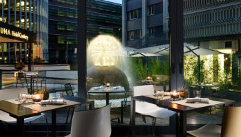 UNAHOTELS Century Milano gay-friendly hotel dining. Tables set near a water fountain. Milan hotel for gay travelers.