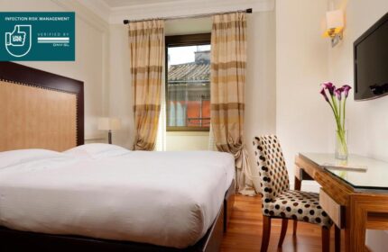 UNAHOTELS Decò Roma gay-friendly room. Pet-friendly hotel with double bed, desk, chair, and window. UNA Safe infection risk management verified.