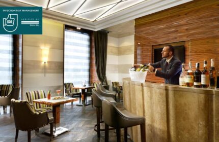 UNAHOTELS Decò Roma's gay-friendly bar. Bartender serves wine. Pet-friendly hotel with stylish decor, tables, and chairs. Ideal for gay travel.