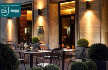 UNAHOTELS Decò Roma gay-friendly, pet-friendly hotel patio. Tables with cocktails, romantic lighting, and lush greenery. Perfect for gay travelers.