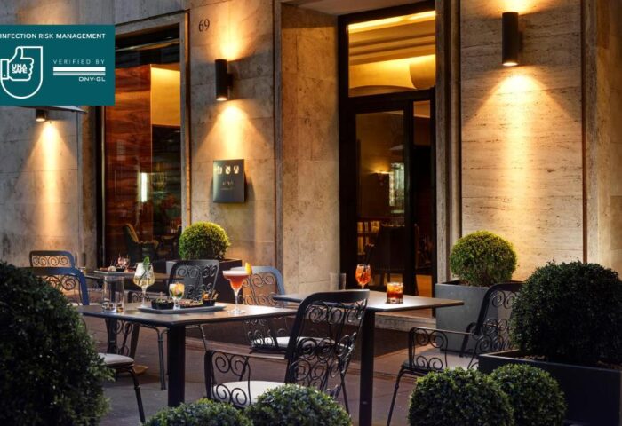 UNAHOTELS Decò Roma gay-friendly, pet-friendly hotel patio. Tables with cocktails, romantic lighting, and lush greenery. Perfect for gay travelers.