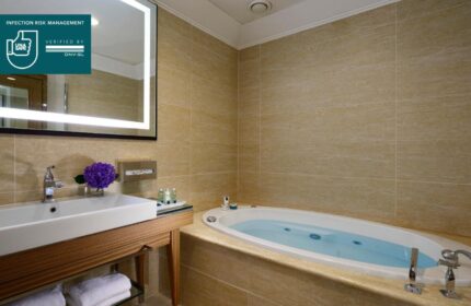UNAHOTELS Decò Roma bathroom with jacuzzi. Gay-friendly, pet-friendly hotel. Sink, mirror, and beige tile. Clean, modern design.