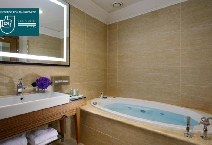 UNAHOTELS Decò Roma bathroom with jacuzzi. Gay-friendly, pet-friendly hotel. Sink, mirror, and beige tile. Clean, modern design.