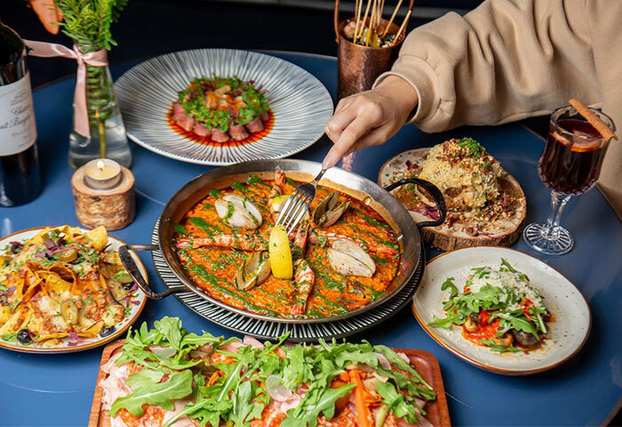 URBN Boutique Shanghai gay-friendly hotel food. Table with paella, salad, nachos, charcuterie board, and mulled wine. Fine dining.