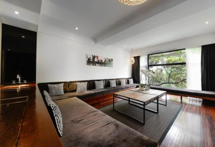 URBN Boutique Shanghai's gay-friendly hotel lounge. Modern interior with a long sofa, coffee table, and view of greenery. Stylish, inviting space.