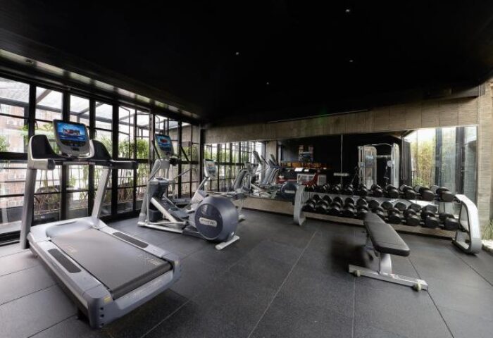 Gym at URBN Boutique Shanghai, a gay-friendly hotel. Treadmills, elliptical machines, weights, and mirrors in a modern workout space.