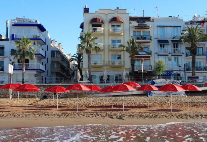 URH Sitges Playa, a gay-friendly, pet-friendly hotel. Beach view with red umbrellas. A great destination for gay men's travel advice.