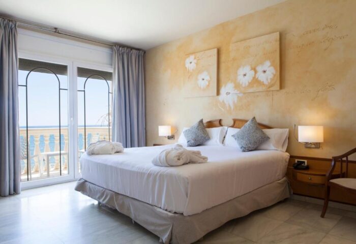 URH Sitges Playa gay-friendly hotel room. Balcony view, double bed with robes. Pet-friendly stay in Sitges. Gay travel advice.