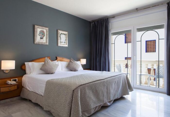 URH Sitges Playa gay-friendly hotel room. King bed, balcony, and modern decor. Pet-friendly accommodations for gay travelers in Sitges, Spain.