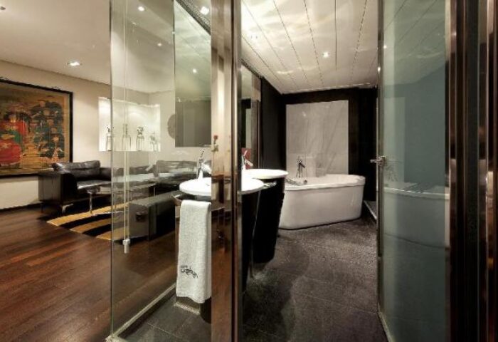 Urban Hotel's stylish suite: Living area with sofa, art, and bathroom with tub. Gay-friendly, pet-friendly hotel design. Modern, chic interior.